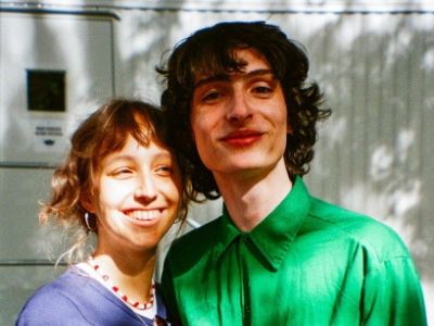Finn Wolfhard is wearing a green shirt whereas, Elsie Richter is wearing a blue dress.